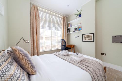 a bedroom with a white bed and a window at Bright Groundfloor 3BR Flat, Brockley, SE London in London