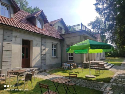 une terrasse avec des chaises et un parasol en face d'une maison dans l'établissement Dworek Cieszków, à Cieszków