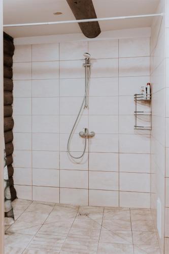 a bathroom with a shower with white tiled walls at Holiday home Migliņas in Kaugurmuiza