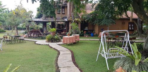 a garden with tables and chairs and a building at Katumbiri Resort in Bogor