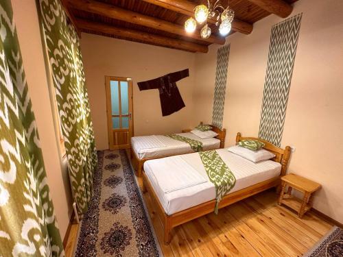 a bedroom with two beds and a cross on the wall at Sarrafon Guest House in Bukhara