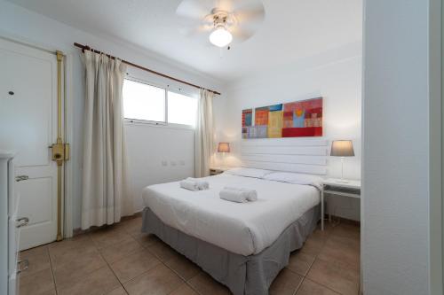 ein weißes Schlafzimmer mit einem Bett und einem Fenster in der Unterkunft Las Adelfas South Beach 2 By CanariasGetaway in San Bartolomé de Tirajana