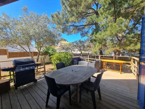 a wooden deck with a picnic table and a grill at Maison 12 pers, Le Phare - 300 mètres des plages in La Tranche-sur-Mer