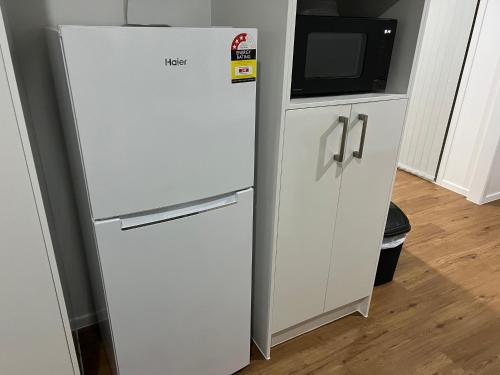 a white refrigerator next to a cabinet with a microwave at Spacious 4 bedroom House in Manukau in Auckland