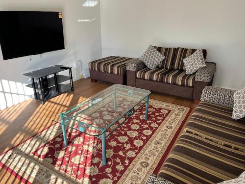 a living room with a couch and a glass coffee table at Spacious 4 bedroom House in Manukau in Auckland