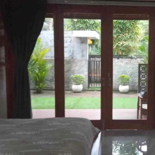 a bedroom with a door open to a patio with plants at Hideaway Batukaras in Pangandaran