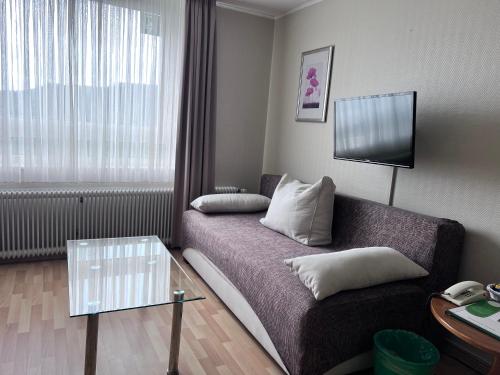 a small living room with a couch and a tv at Waldhotel Sonnenberg in Bollendorf