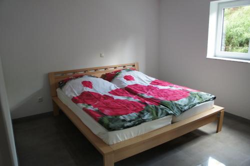 Una cama con un edredón con rosas rojas. en 2- Zimmer-Wohnung, en Weilerswist