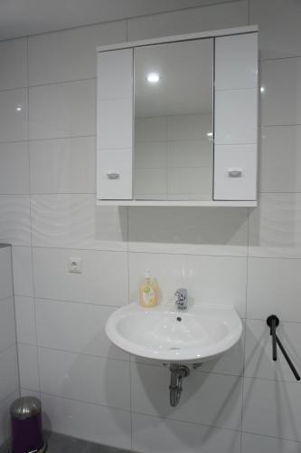 a white sink in a white tiled bathroom at 2- Zimmer-Wohnung in Weilerswist