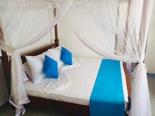 a bedroom with a bed with blue and white pillows at Soul Inn in Ahangama
