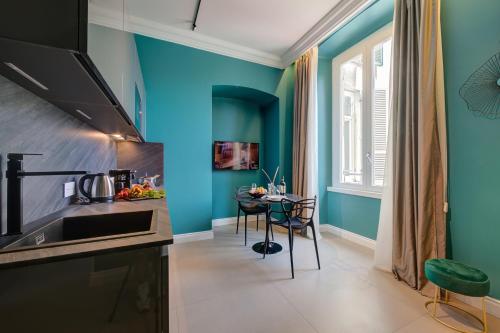 a kitchen with blue walls and a table with chairs at Seven Suites Apartments - Via Matteotti 178 in Sanremo