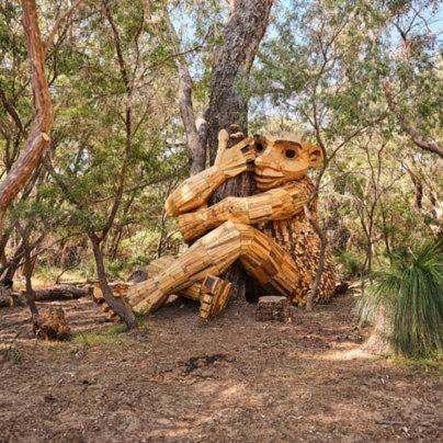 a wooden statue of a bear sitting in the woods at Relaxing Getaway Beachfront Access Multi Family Pets Mandurah in Mandurah