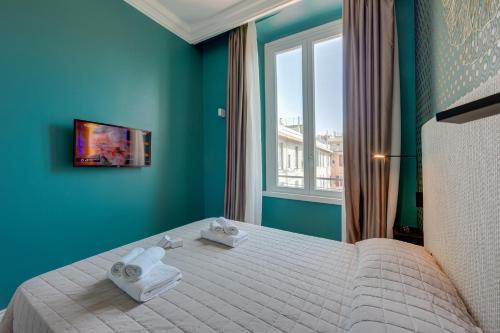 a bedroom with a bed with blue walls and a window at Seven Suites Apartments - Via Matteotti 178 in Sanremo