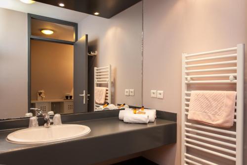 La salle de bains est pourvue d'un lavabo et d'un miroir. dans l'établissement Domaine Lou Capitelle & Spa, à Vogüé