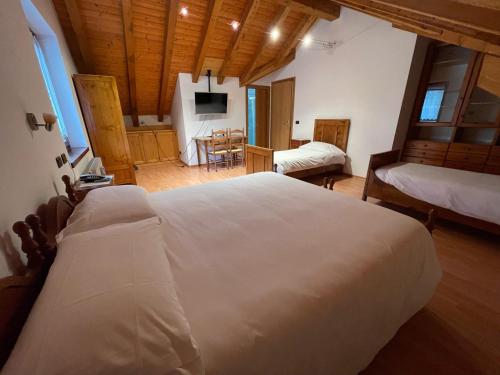 a bedroom with a large white bed in a room at Albergo Nuoitas in Forni di Sopra