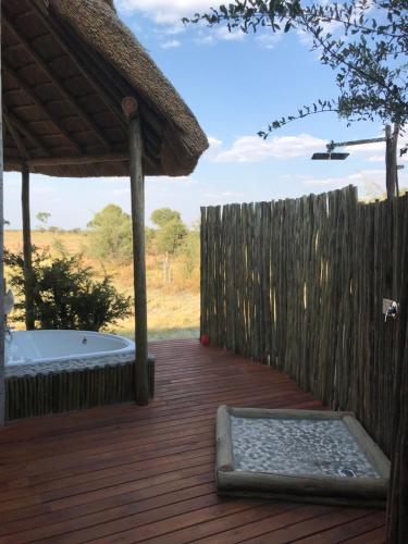 a deck with a hot tub and a fence at Mababe River Lodge in Mababe