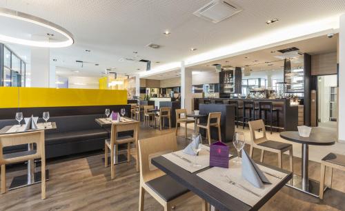 a restaurant with tables and chairs and a yellow wall at Star G Hotel Premium München Domagkstraße in Munich