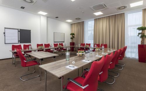 a conference room with a long table and red chairs at Star G Hotel Premium München Domagkstraße in Munich