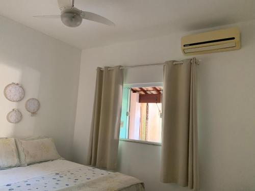 - une chambre avec un lit, un ventilateur de plafond et une fenêtre dans l'établissement Casa de Férias para sua Família e seu Pet!, à Itatiaia