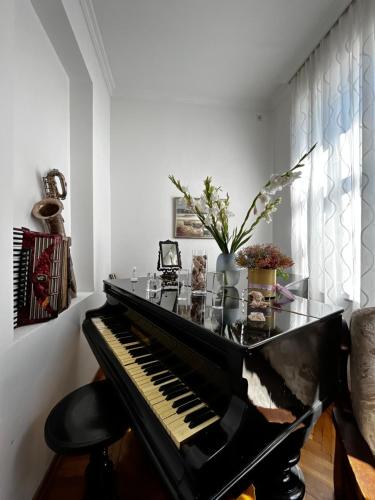 un piano negro en una sala de estar con una silla en Guest House Hello en Kutaisi