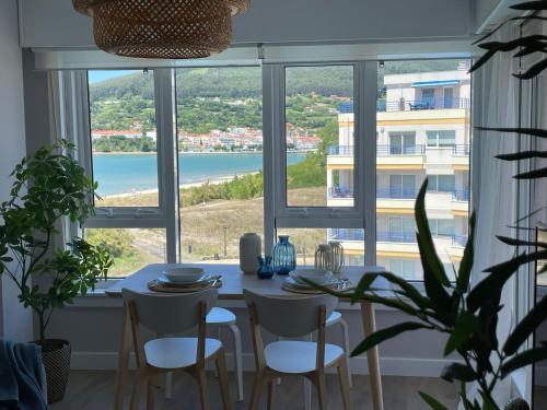a dining room with a table and chairs and a large window at Apartamento con vistas al mar B5 Urb Puerto Azul in Cedeira