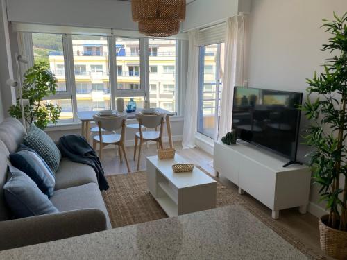 sala de estar con sofá y TV de pantalla plana en Apartamento con vistas al mar Urb Puerto Azul B5, en Cedeira