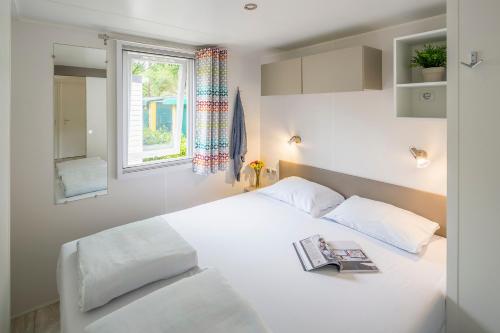 1 dormitorio con cama blanca y ventana en Camping Marvilla Parks Friese Meren - Roan en Wijckel