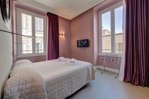 a bedroom with a bed with pink walls and windows at Seven Suites Apartments - Via Matteotti 178 in Sanremo
