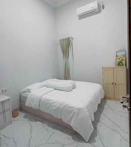 una camera bianca con un letto e una finestra di Holiday Homestay Singkawang a Sedau
