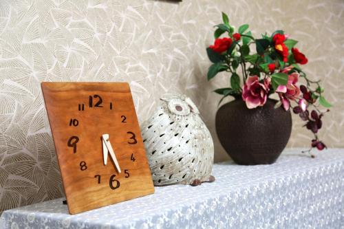 a table with a clock and a vase with flowers at Hotel Access in Iwaki