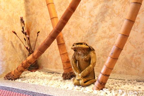a statue of a frog sitting next to bamboo poles at Hotel Access in Iwaki