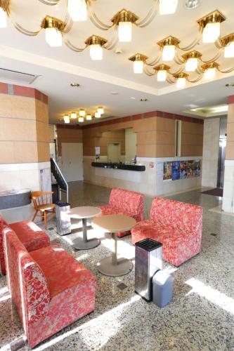 a lobby with red chairs and tables in a building at Hotel Access in Iwaki