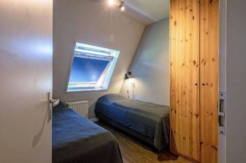 een kleine slaapkamer met een bed en een raam bij Heerlijk appartement op Texel vlakbij bos en zee. in De Koog