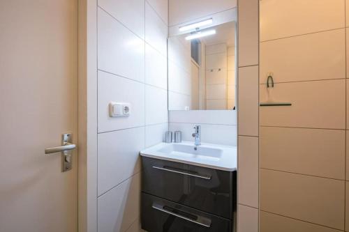 a small bathroom with a sink and a mirror at Heerlijk appartement op Texel vlakbij bos en zee. in De Koog