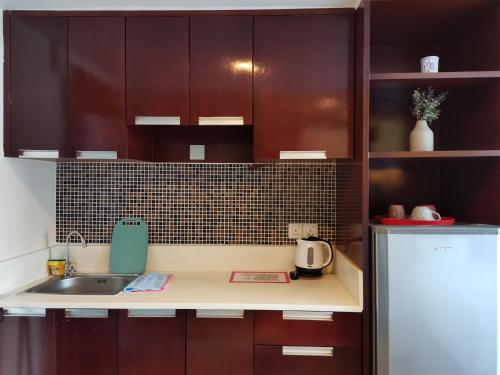 a kitchen with brown cabinets and a sink and a refrigerator at Greenage MingSuite 明绿时代套房 Kota Kinabalu 亚庇市中心 in Kota Kinabalu