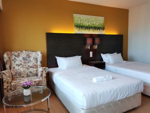 a room with two beds and a chair and a glass table at Greenage MingSuite 明绿时代套房 Kota Kinabalu 亚庇市中心 in Kota Kinabalu