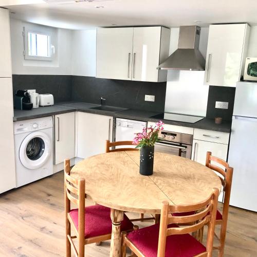 - une cuisine avec une table en bois, des chaises et un évier dans l'établissement La rocaille du château, à Gréoux-les-Bains