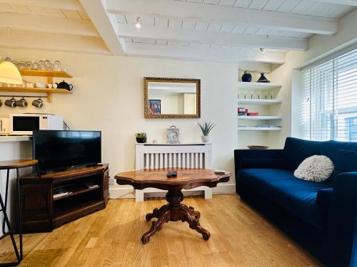 a living room with a blue couch and a table at Alexander cottage in Penryn