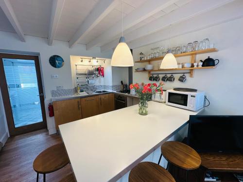a kitchen with a counter with chairs and a microwave at Alexander cottage in Penryn