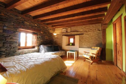 1 dormitorio con cama y pared de piedra en Hotel Rural La Encantada en Riaza en Becerril