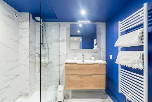 a blue bathroom with a sink and a shower at Le Loft du Parvis : spacieux, central & élégant. in Dijon