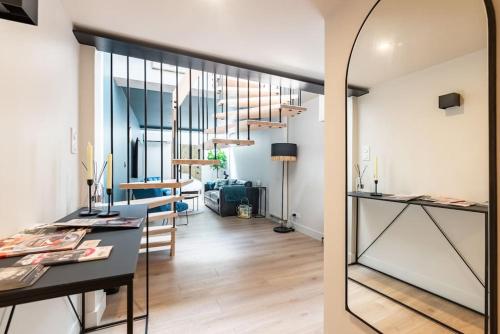 Il comprend une cuisine et un salon avec une table et un miroir. dans l'établissement Le Loft du Parvis : spacieux, central & élégant., à Dijon