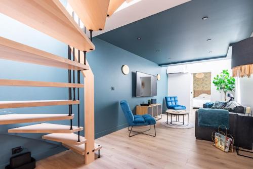 een woonkamer met blauwe muren en een trap bij Le Loft du Parvis : spacieux, central & élégant. in Dijon