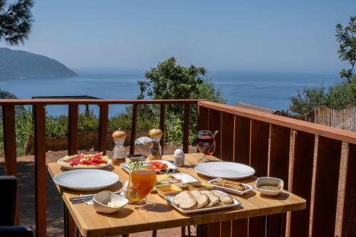 una mesa de madera con comida y bebida en el balcón en Goat Bungalow and Camping en Faralya