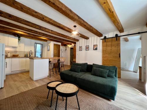 un salon avec un canapé vert et une cuisine dans l'établissement Les Poutres de Cuvier, à Montbéliard