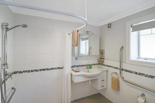 La salle de bains blanche est pourvue d'un lavabo et d'une douche. dans l'établissement Kerikeri Park Lodge, à Kerikeri