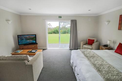 a hotel room with a large bed and a television at Kerikeri Park Lodge in Kerikeri
