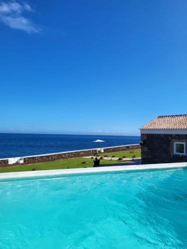a swimming pool with the ocean in the background at Azores 5 estrelas in Porto Judeu