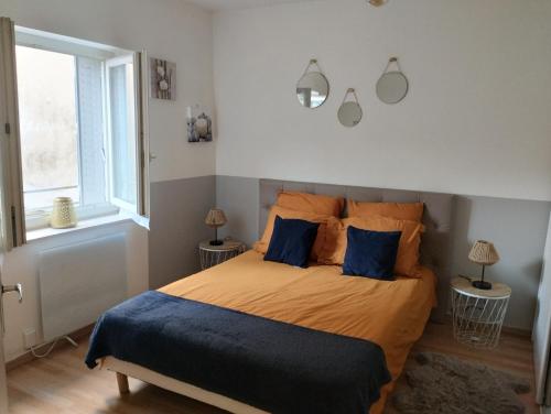 een slaapkamer met een bed met oranje lakens en blauwe kussens bij ABSL Appartement in Villefranche-sur-Saône