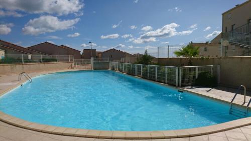 a large pool with blue water in a building at Magnifique maison vue sur la mer avec piscine commune à 800m de la plage in Fleury